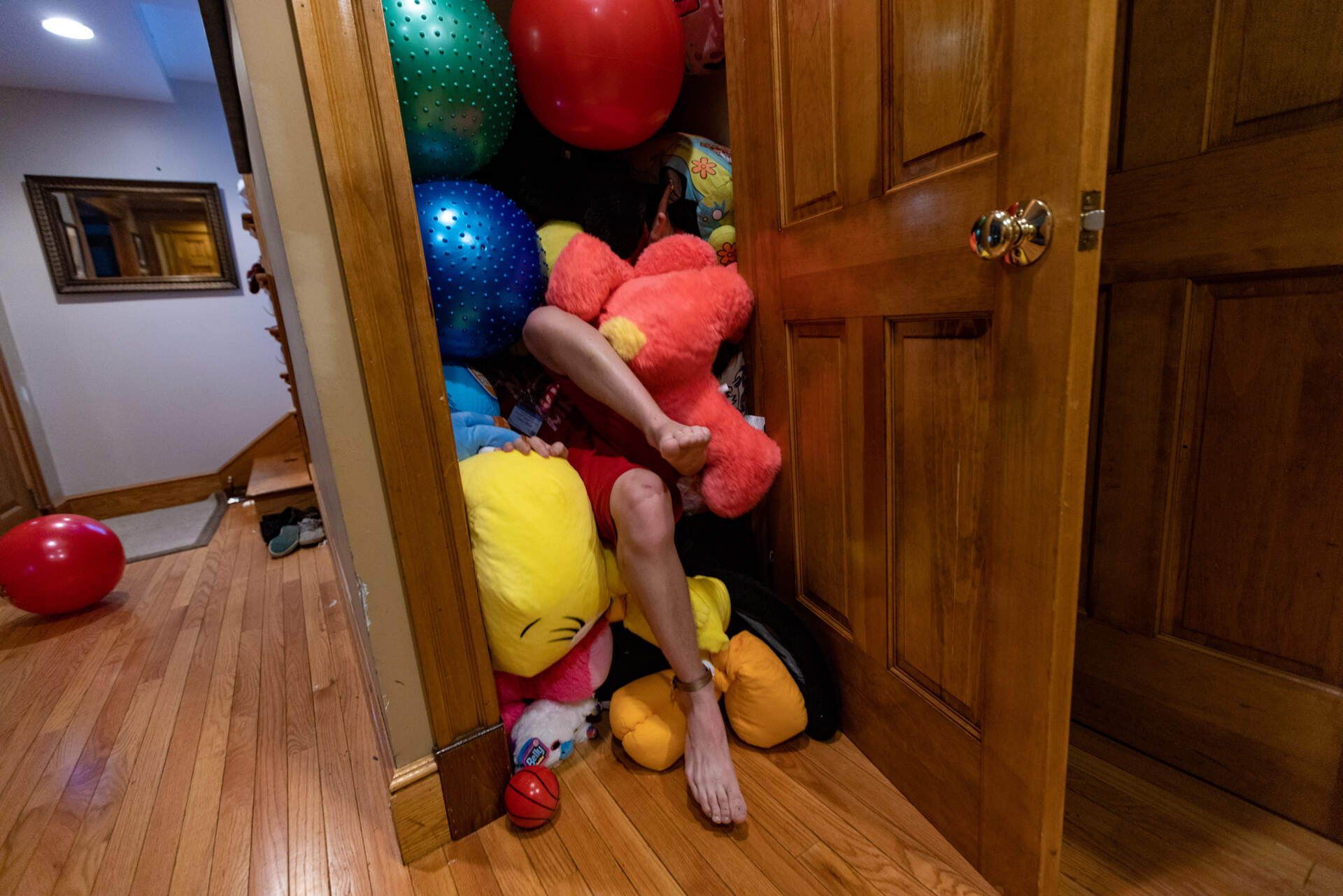 Connor Biscan climbs into the sensory closet at his family home. It's filled with plushy toy animals and balls. (Jesse Costa/WBUR)