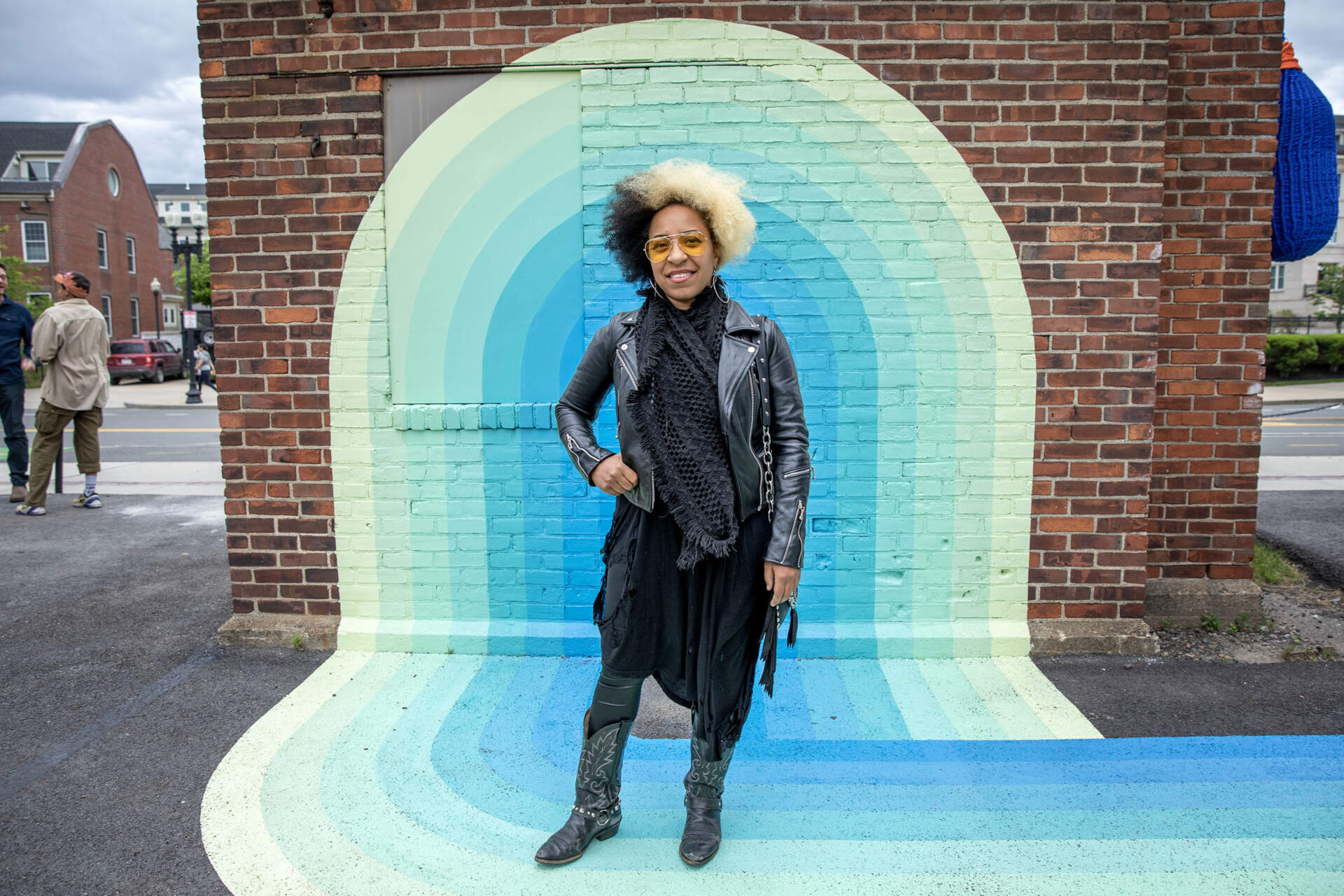 Artist Massiel Grullón stands at one end of her ground mural “Knotical Waves” at Lot Lab, near the Charlestown Navy Yard. (Robin Lubbock/WBUR)