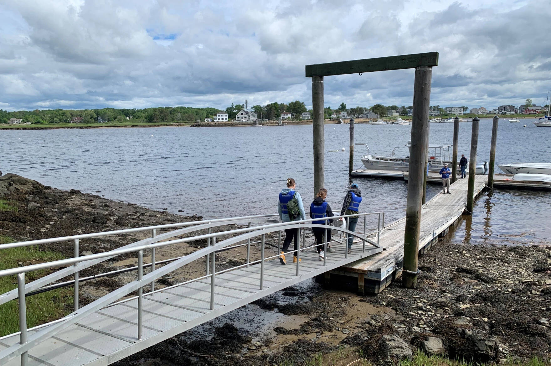 A group of University of New England students carry a buoy that's been designed to detect sharks in real time to the school's research vessel docked along the Saco River. (Nicole Ogrysko/Maine Public)