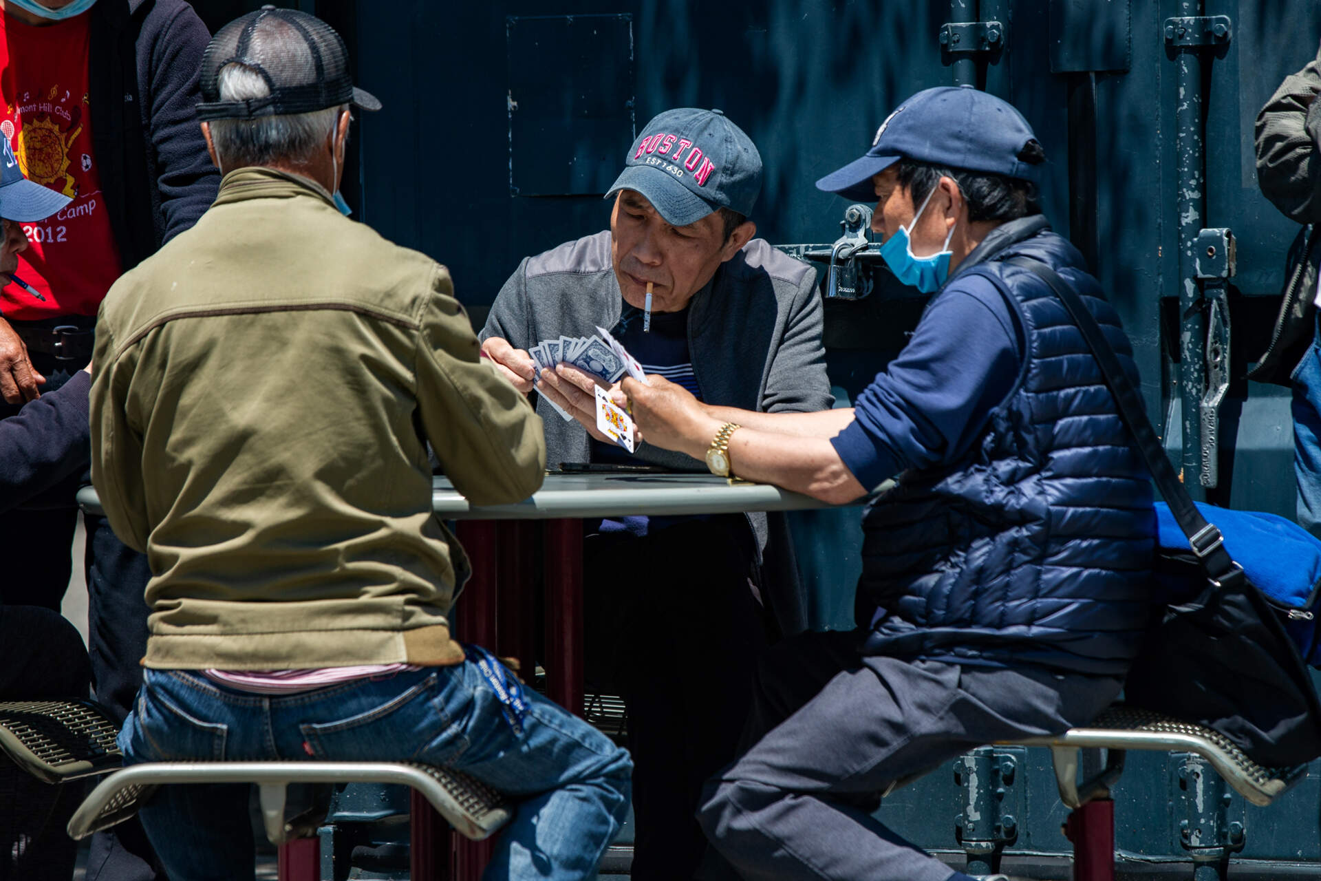 Men playing cards at a table on the Chinatown Plaza on the Rose Kennedy Greenway. (Jesse Costa/WBUR)