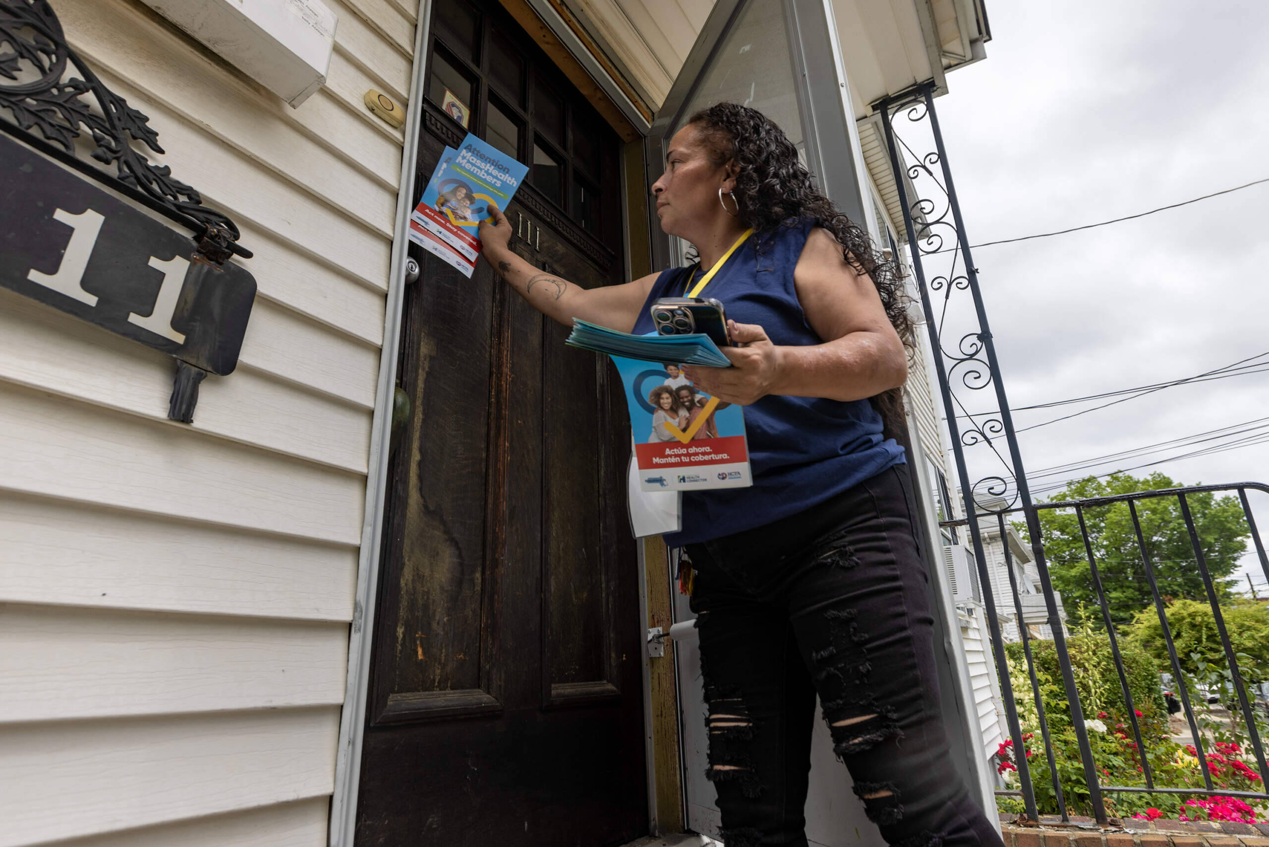 Outreach worker Carrie Perez leaves information about MassHealth at the door of a home in Revere. (Jesse Costa/WBUR)