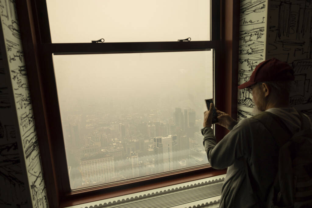 A person takes pictures of New York City in a haze-filled sky from the Empire State Building observatory, Wednesday, June. 7, 2023, in New York. Smoke from Canadian wildfires poured into the U.S. East Coast and Midwest on Wednesday, covering the capitals of both nations in an unhealthy haze, holding up flights at major airports and prompting people to fish out pandemic-era face masks. (Yuki Iwamura/AP)