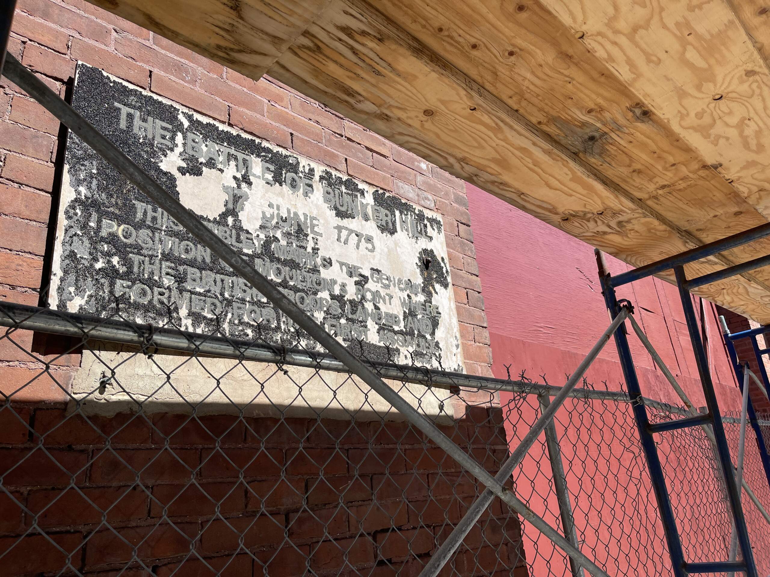 A plaque marking the Battle of Bunker Hill in Charlestown is worn and hard to read. (Rupa Shenoy/WBUR)
