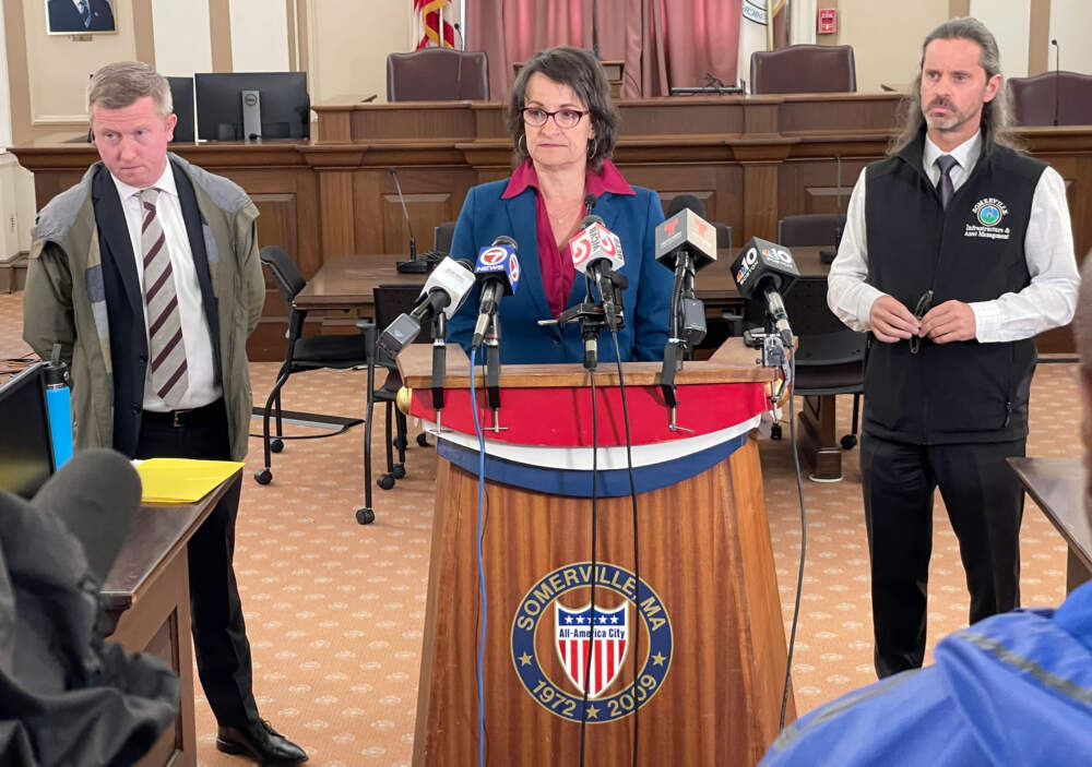 Somerville Mayor Katjana Ballantyne, flanked by the district's interim superintendent Jeff Curley, left, and Rich Raiche, the city's director of infrastructure and asset management. (Max Larkin/WBUR)