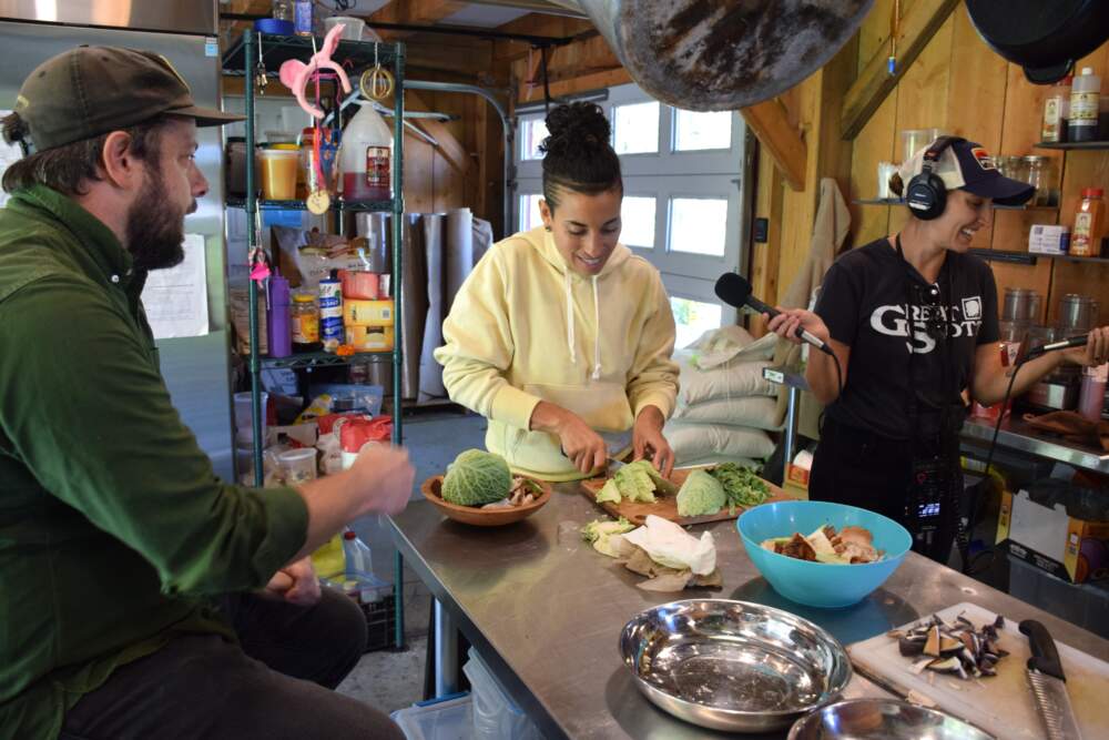 Naima Pennim, program director of Soul Fire Farm, chopping vegetables with Ben Brock Johnson and Amory Sivertson.
