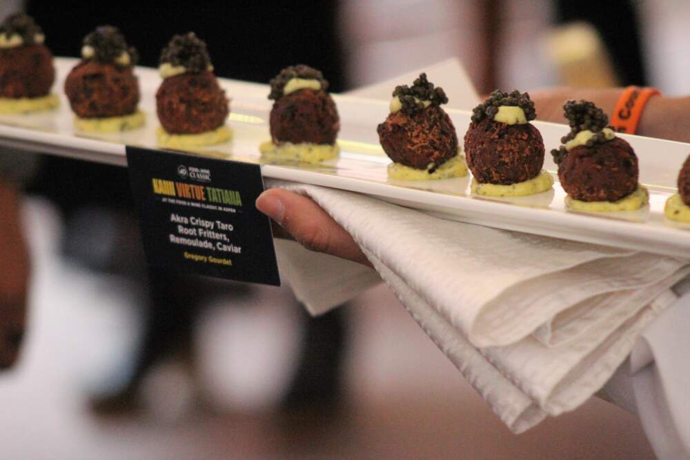 A server presents akra, or crispy taro root fritters, with remoulade and caviar by chef Gregory Gourdet. (Kaya Williams/Aspen Public Radio)