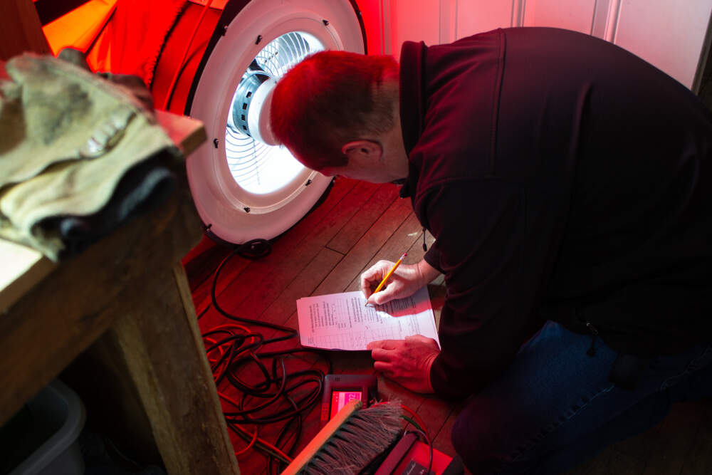 Energy auditor BJ Estey of Aroostook County Action Program takes notes during a blower door test, which checks a house for air leaks, in Castle Hill, Maine.