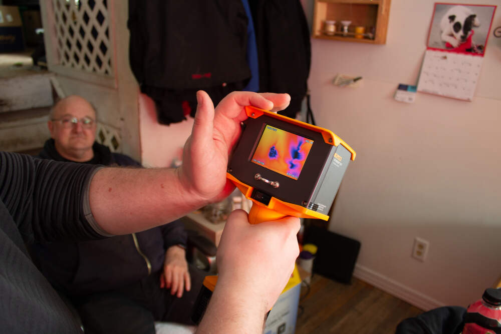 A thermal imager shows cold air leaking through an electrical outlet and hidden gaps in drywall at the Castle Hill, Maine, home of Bob Moody, left, during an free energy audit he received in late March from Aroostook County Action Program. 