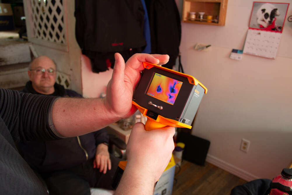 A thermal imager shows cold air leaking through an electrical outlet and hidden gaps in drywall at the Castle Hill, Maine, home of Bob Moody, left, during an free energy audit he received in late March from Aroostook County Action Program.