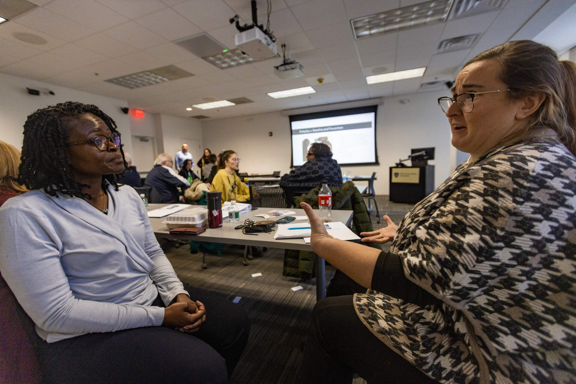 Zita Tiamuh (left), who works in program development at William James College, and Stephanie Nguyen, a psychologist, act out the roles of veteran and therapist during a portion of the suicide prevention training course. (Jesse Costa/WBUR)