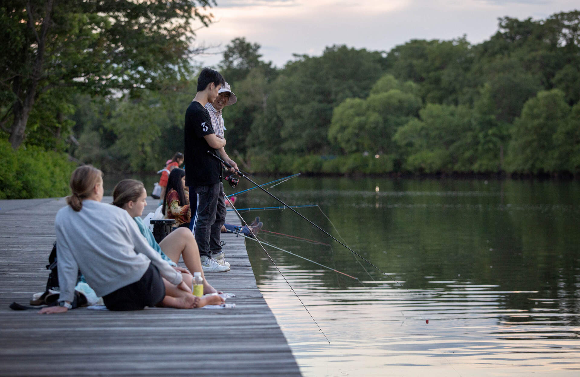 People fishing on a summer evening on the Charles River in Allston. (Robin Lubbock/WBUR)