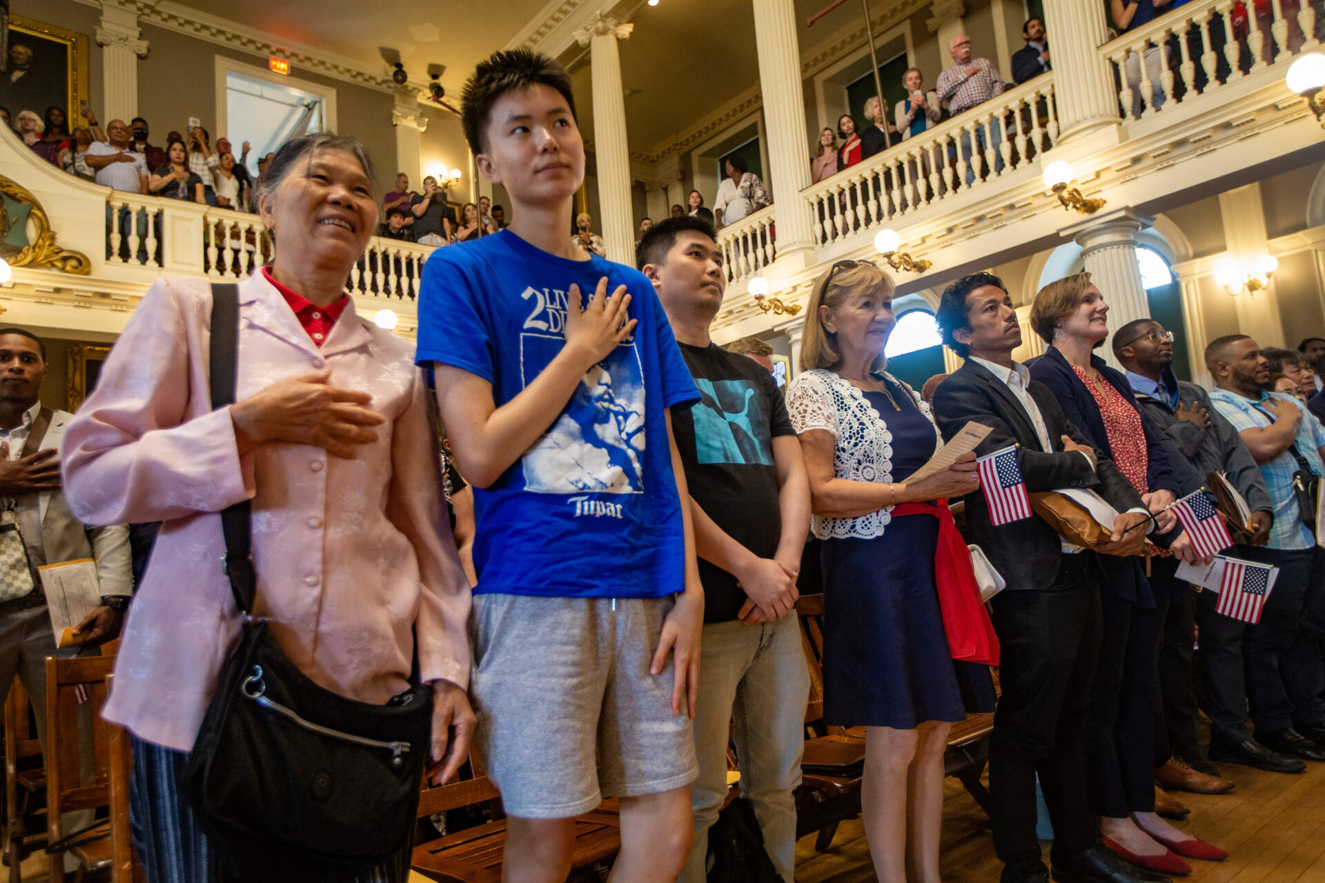 Naturalization applicants stand to recite the Pledge of Allegiance during a naturalization ceremony at Faneuil Hall. (Jesse Costa/WBUR)