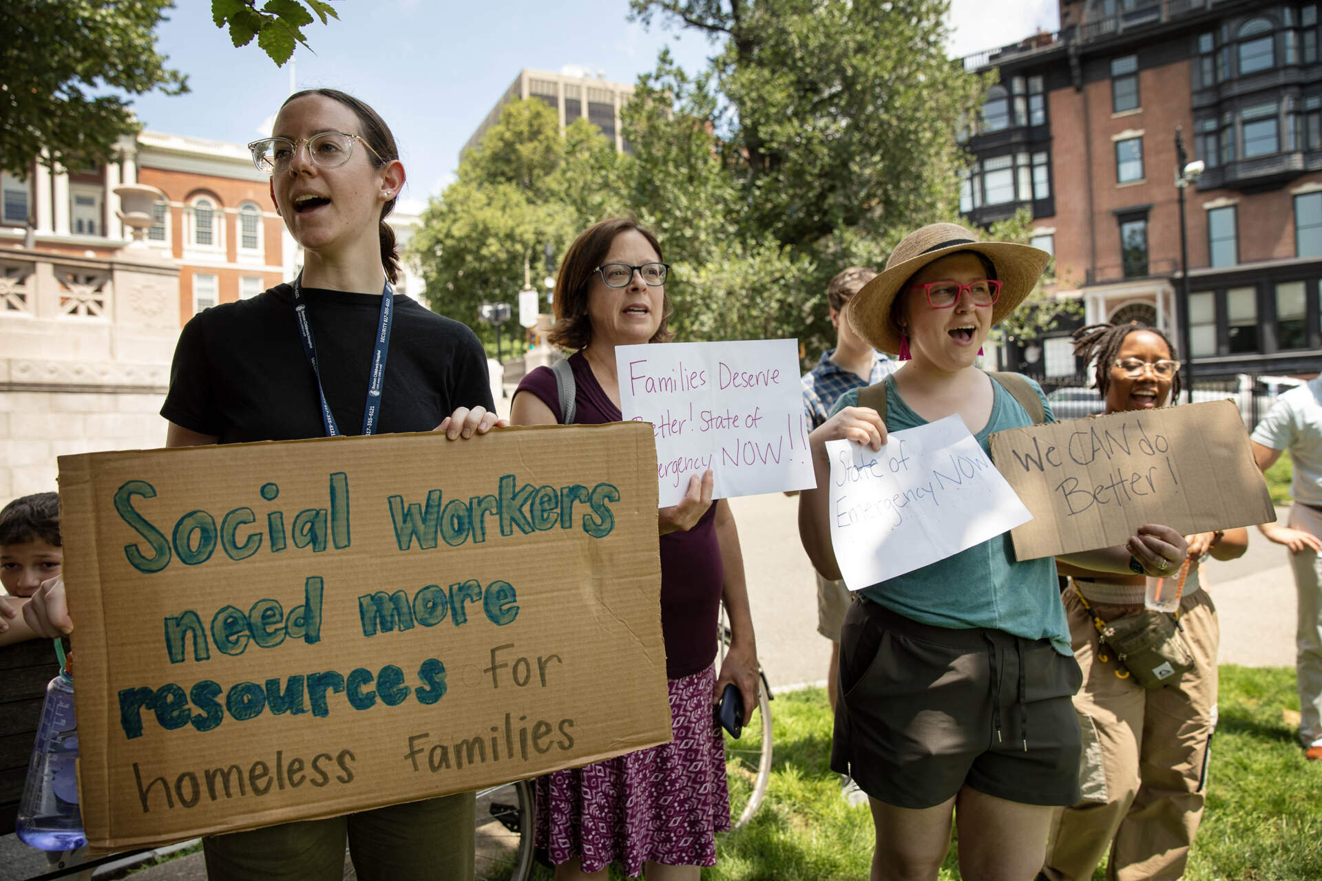 Protesters hold up signs at a rally of health care and community workers on Boston Common by the Massachusetts State House. (Robin Lubbock/WBUR)