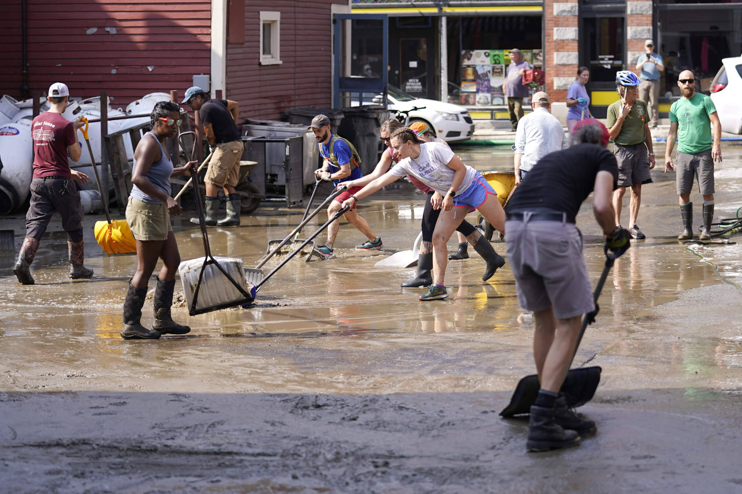 Volunteers clean up a downtown parking area on the banks of the Winooski River, Wednesday, July 12, 2023, in Montpelier, Vt. (Charles Krupa/AP)
