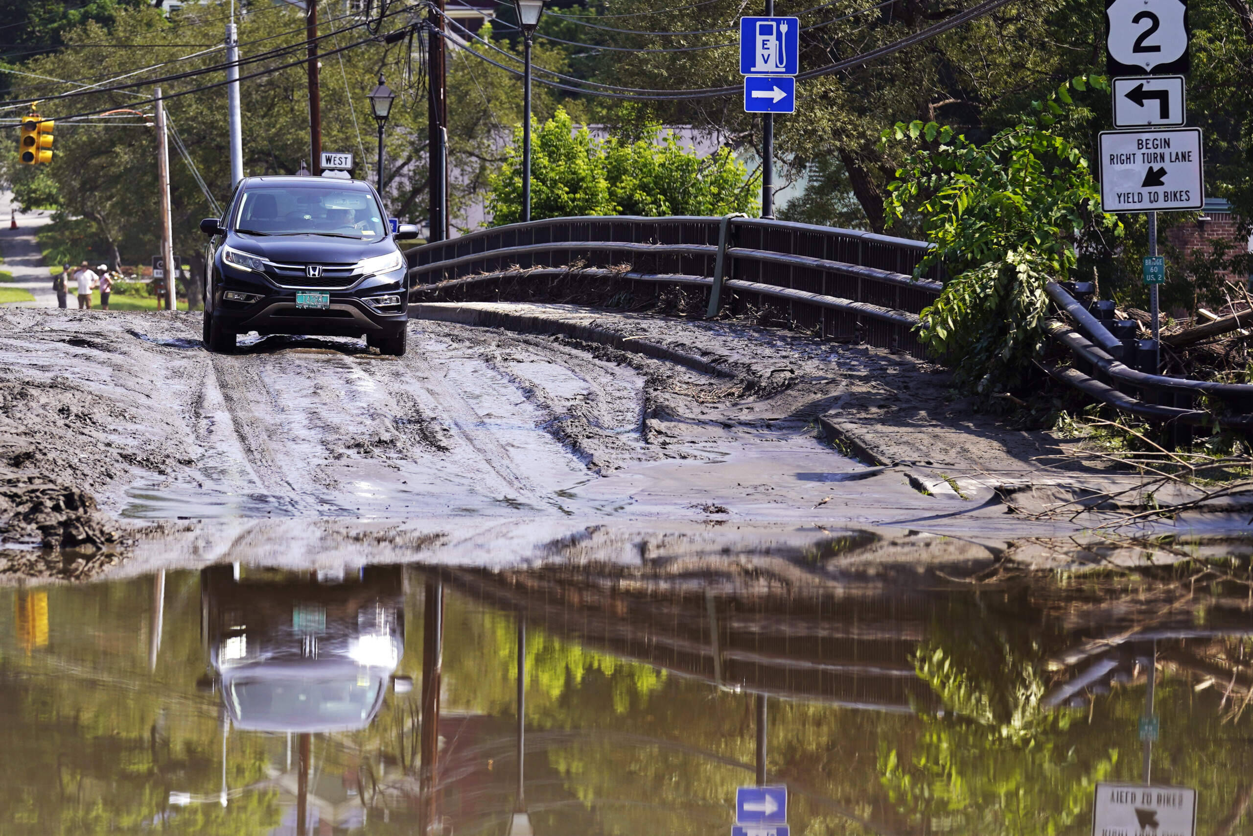 A driver stops on a mud-covered bridge while deciding whether to drive through flood waters of the Winooski River, Wednesday, July 12, 2023, in Montpelier, Vt. (Charles Krupa/AP)
