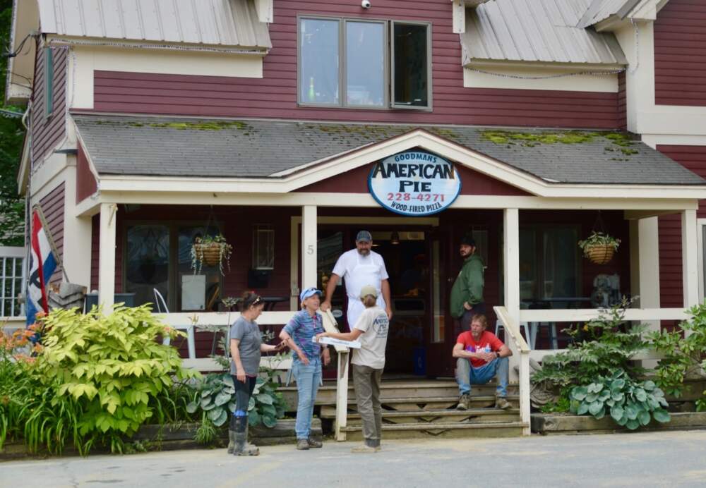 Craig Goodman (wearing a white apron) chats with locals at his pizzaria in Ludlow. Goodman says he's been in business for 24 years and his first restaurant was completely destroyed by Tropical Storm Irene. "It was horrible, really really tough." This time he escaped any damage and so was offering free pizza to anyone in the community who came to help clean up on Wednesday. "I was lucky and I wanted to give back. This community is amazing." (Nina Keck/Vermont Public)