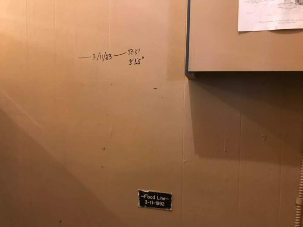Inside Ondine Salon in Montpelier, the lower plaque indicates the high-water mark from the historic flood of 1992. Salon owner Maya Boffa used a marker to show the peak water level from Tuesday. (Peter Hirschfeld/Vermont Public)
