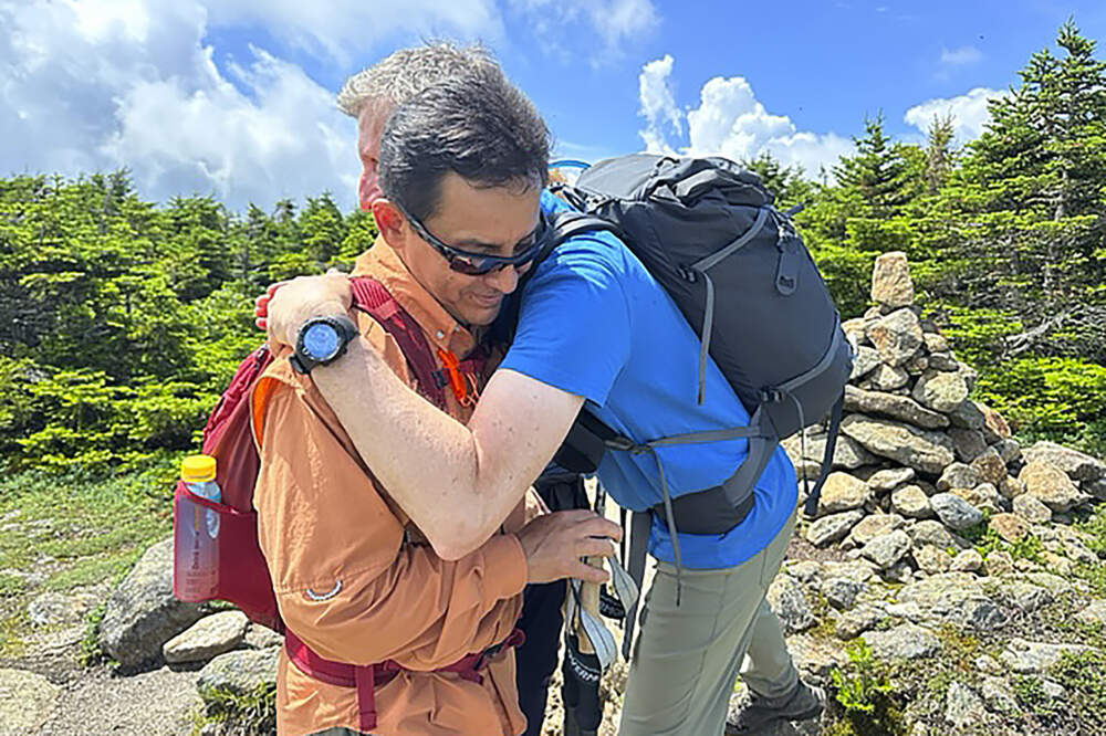 Jorge Sotelo, front, hugs Andrew Barlow, behind, at the summit of New Hampshire's Mount Pierce, in Coos County, N.H., Saturday, July 8, 2023. Barlow moderates the Hiking Buddies NH 48 Facebook group, which is partnering with Sotelo and his wife to organize a July 29 hike to honor the couple's daughter.(Holly Ramer/AP)