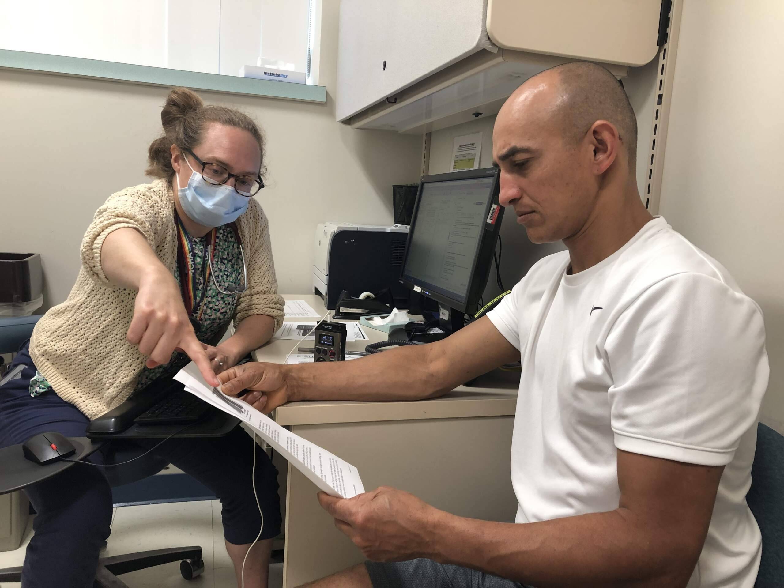 Dr. Rebecca Rogers highlights hydration tips for Luciano Gomes, who works in construction. (Martha Bebinger/WBUR)