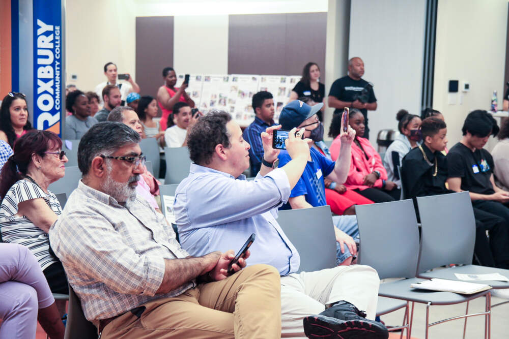 Ruben Flores taking a photo as students present their findings. (WBUR/Emily Piper-Vallillo)