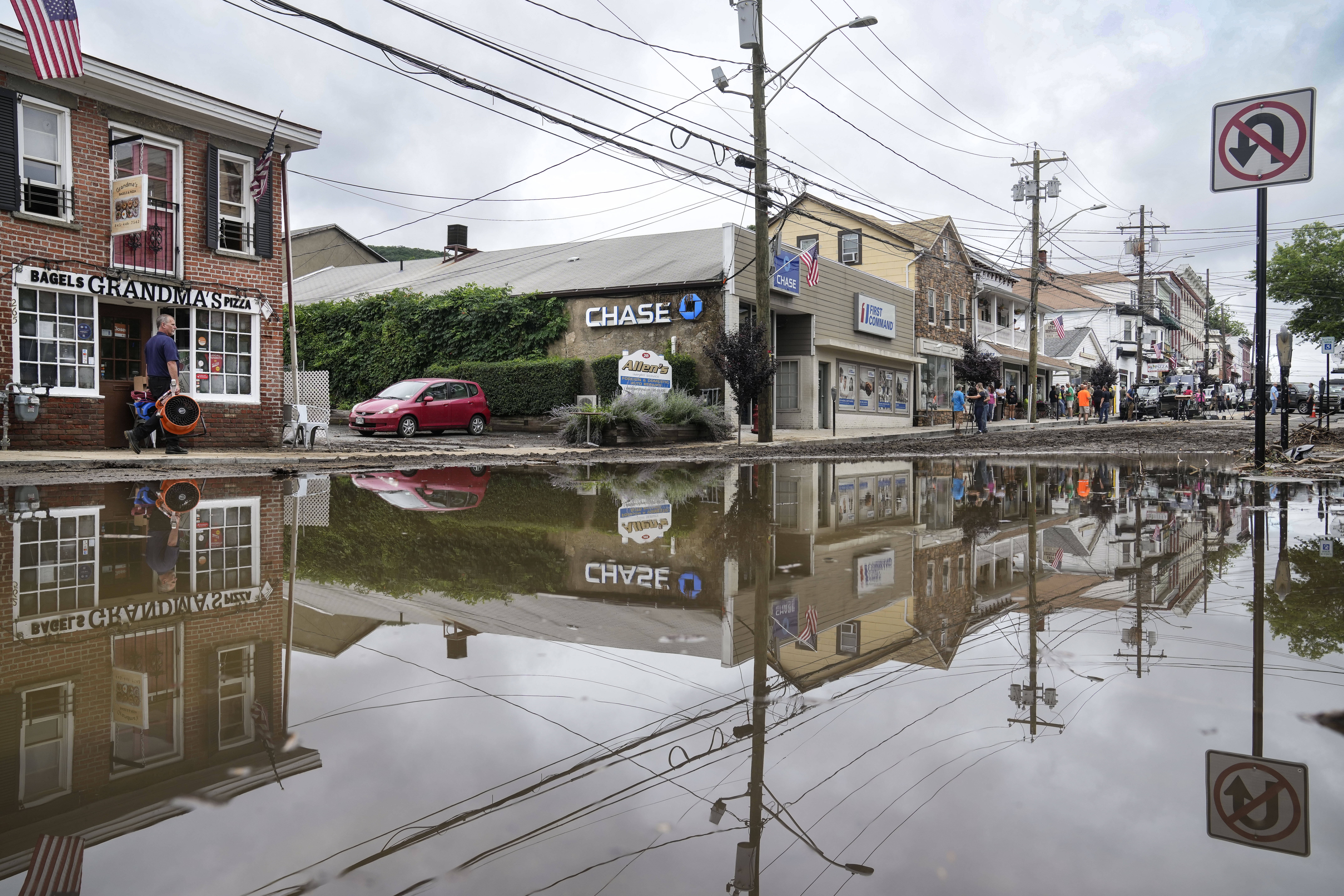 Residents, journalists, and emergency service workers walk around a flooded Main Street, July 10, 2023, in Highland Falls, N.Y. (John Minchillo/AP)