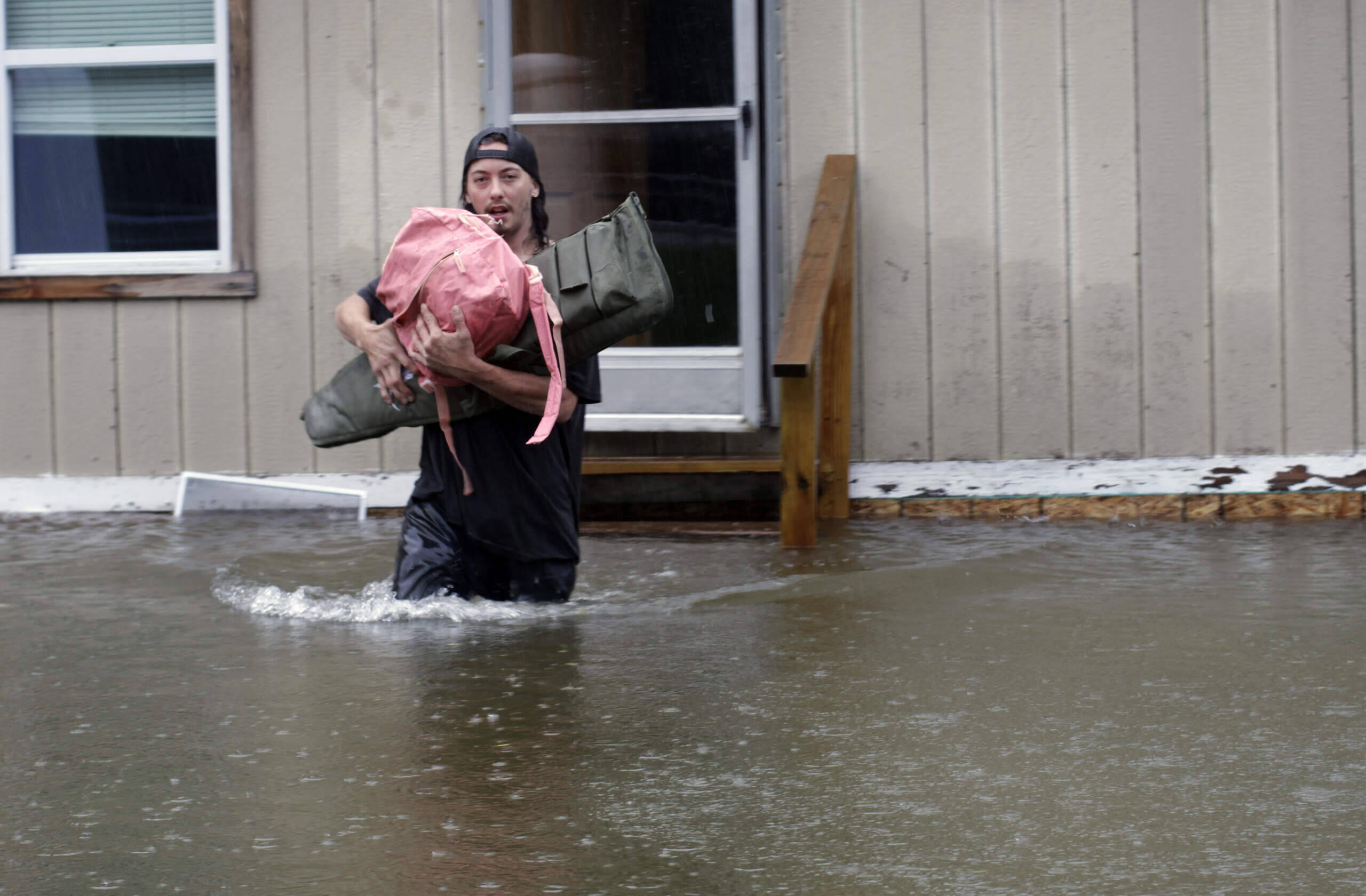 A man carries belongings through floodwaters from a home in Bridgewater, Vt., July 10, 2023. (Hasan Jamali/AP)