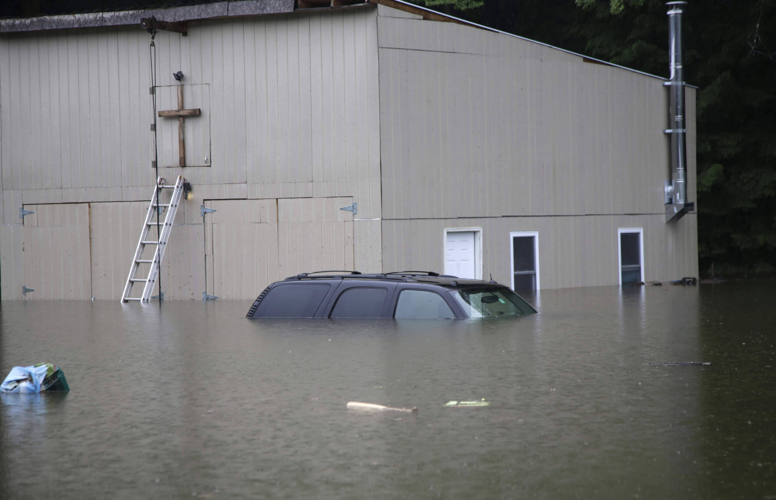 Floodwaters rise in Bridgewater, Vt., on July 10, 2023, submerging parked vehicles and threatening homes near the Ottauquechee River. (Hasan Jamali/AP)