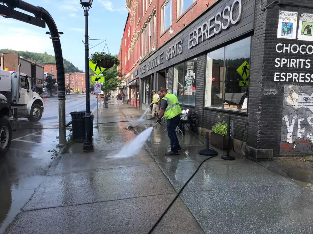 Montpelier city workers power-wash sludge on sidewalks left behind by flood waters on Wednesday. (Peter Hirschfeld/Vermont Public)