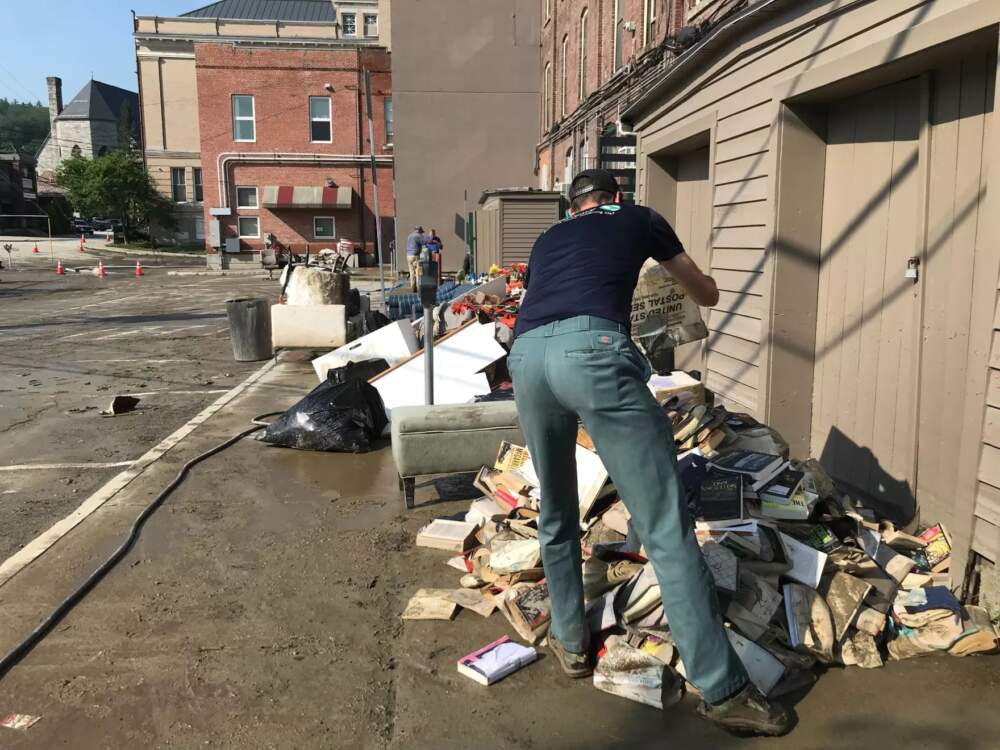 A volunteer dumps destroyed inventory from Bear Pond Books in a parking lot behind the popular store on Wednesday. (Peter Hirschfeld/Vermont Public)