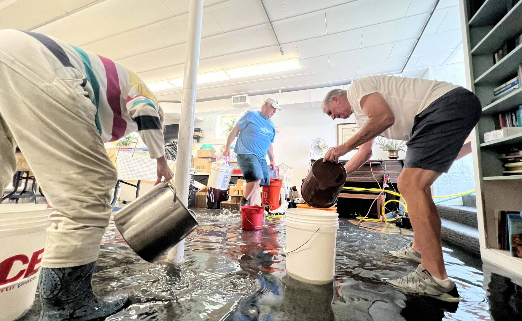 Volunteers use buckets and a pasta pot to bail out the basement of Second Congregational Church in Londonderry on the morning of July 11, 2023. (Brian Stevenson And Kyle Ambusk/Vermont Public)