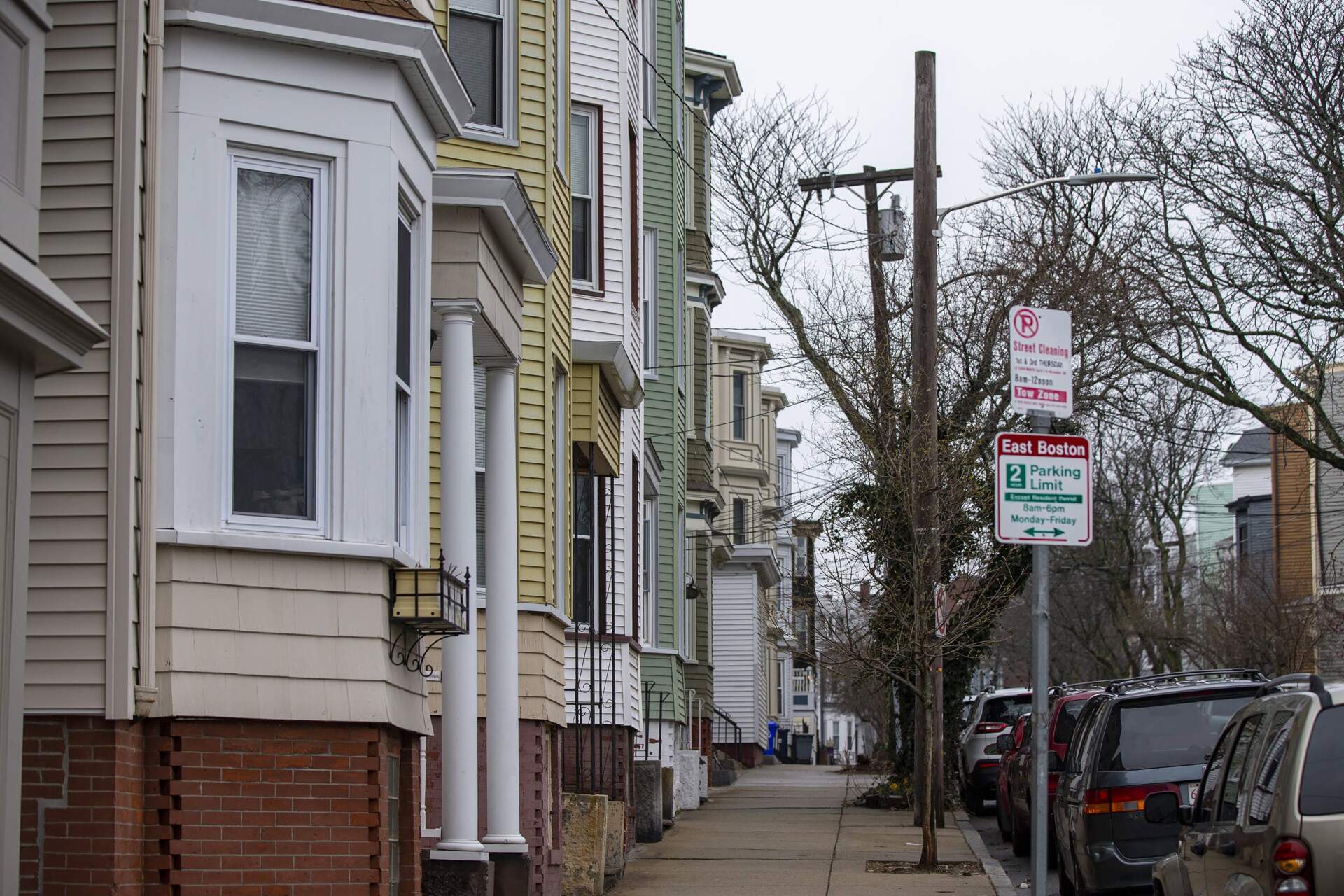 A parking sign outside three-decker apartments in East Boston. (Jesse Costa/WBUR)