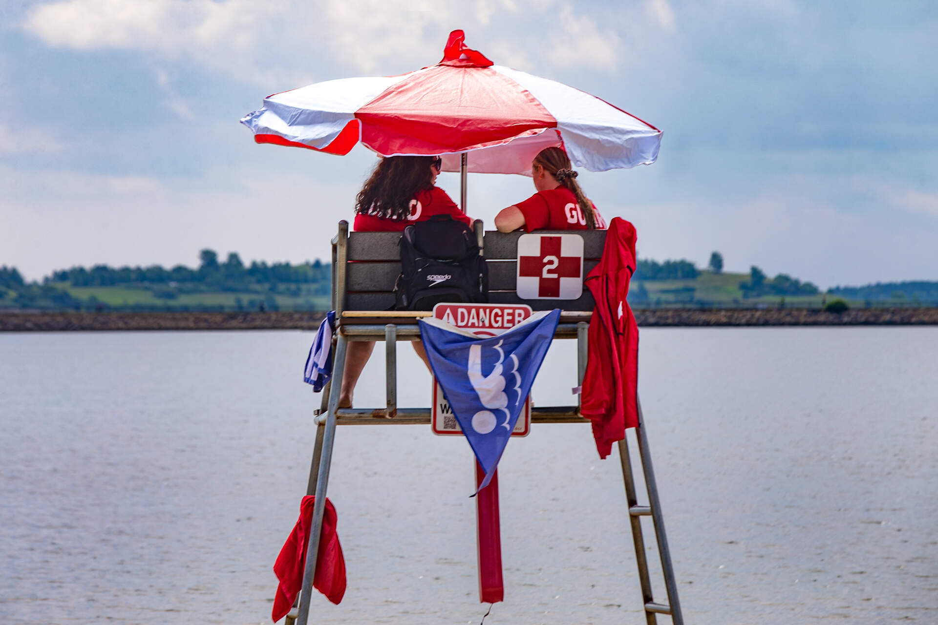 Two lifeguards chat on a lifeguard chair at Pleasure Bay Beach in South Boston. (Jesse Costa/WBUR)