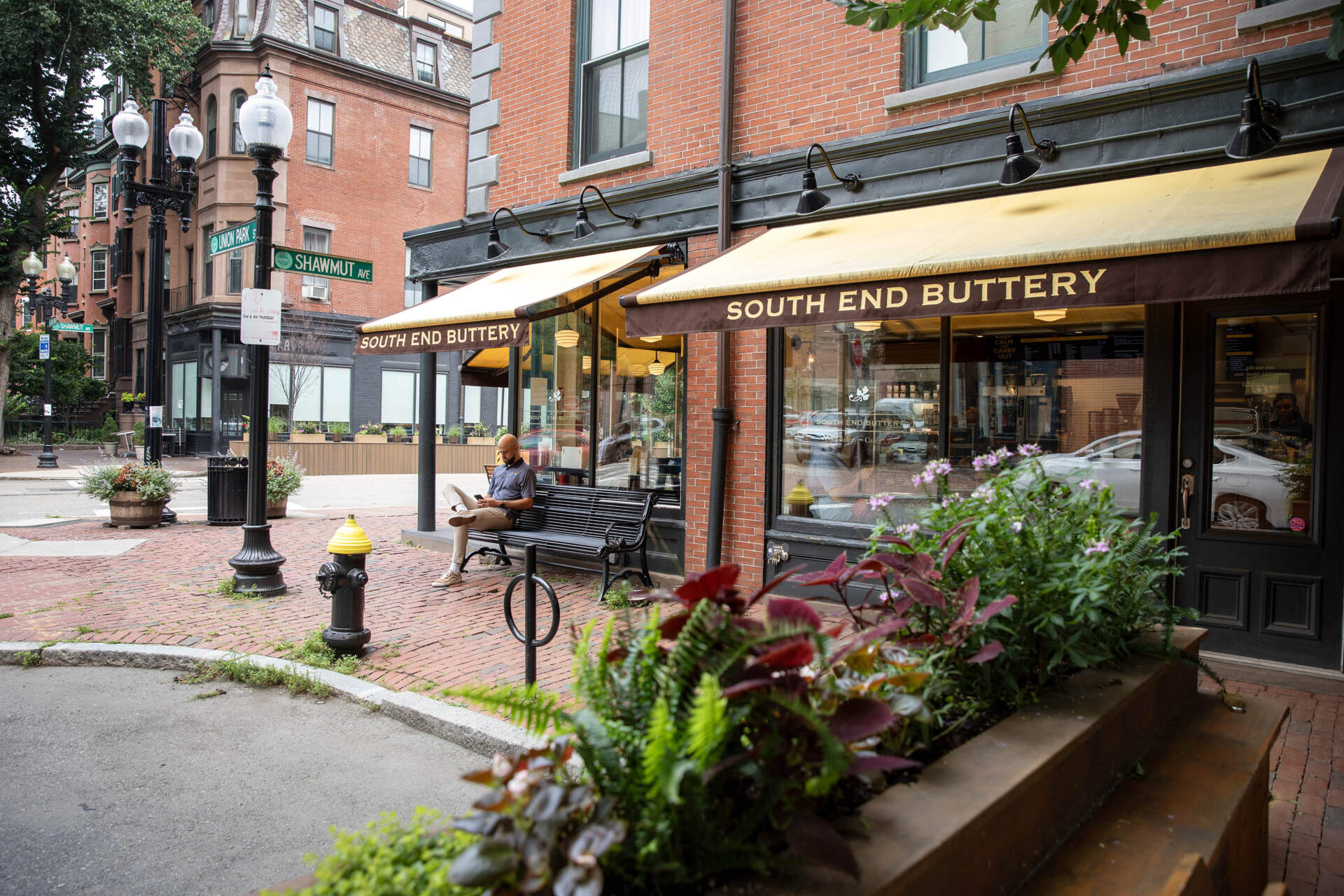 A man sits in the shade outside the South End Buttery on Shawmut Avenue in Boston. (Robin Lubbock/WBUR)