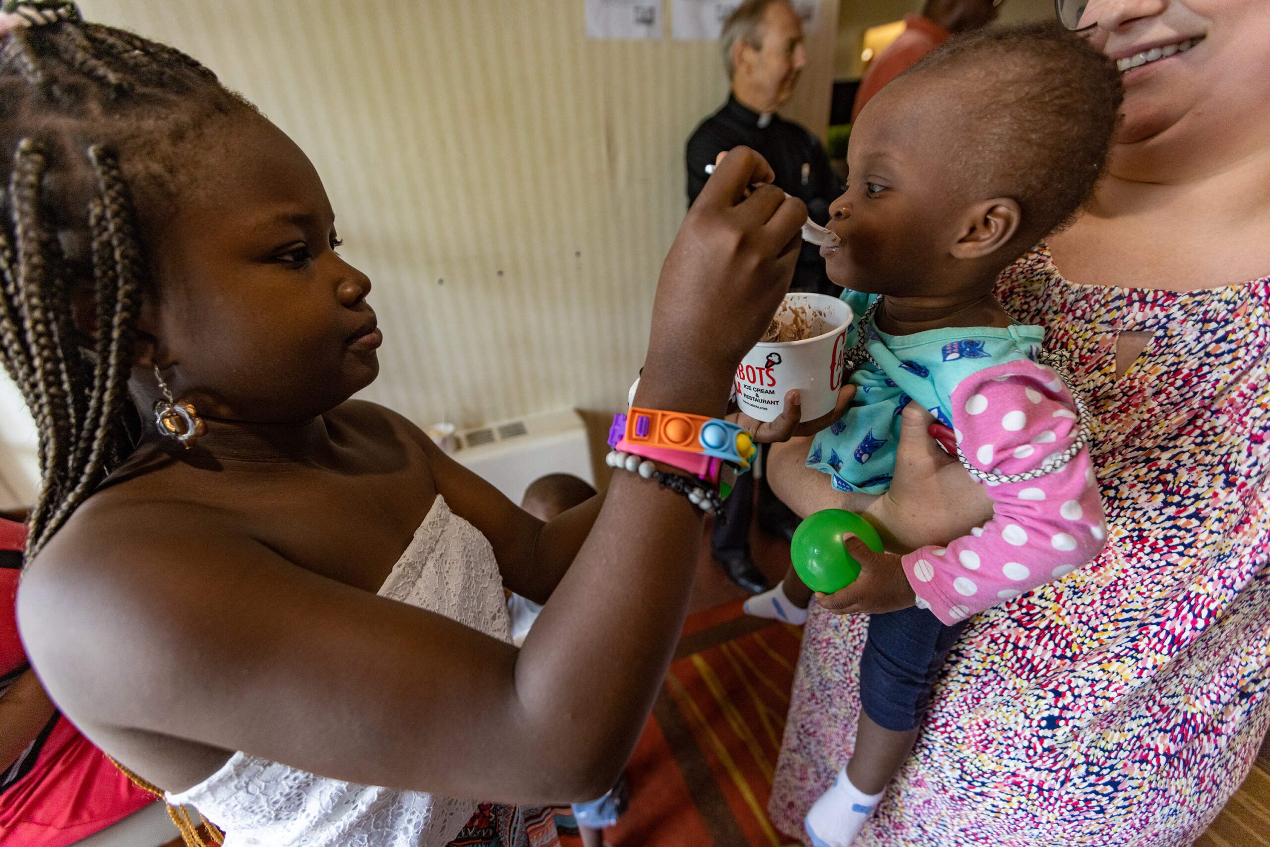 Michela Charles, 9, feeds ice cream to one-year-old Lourdes Mica during an ice cream social at the Catholic Charities new emergency shelter for the homeless in Brighton. (Jesse Costa/WBUR)