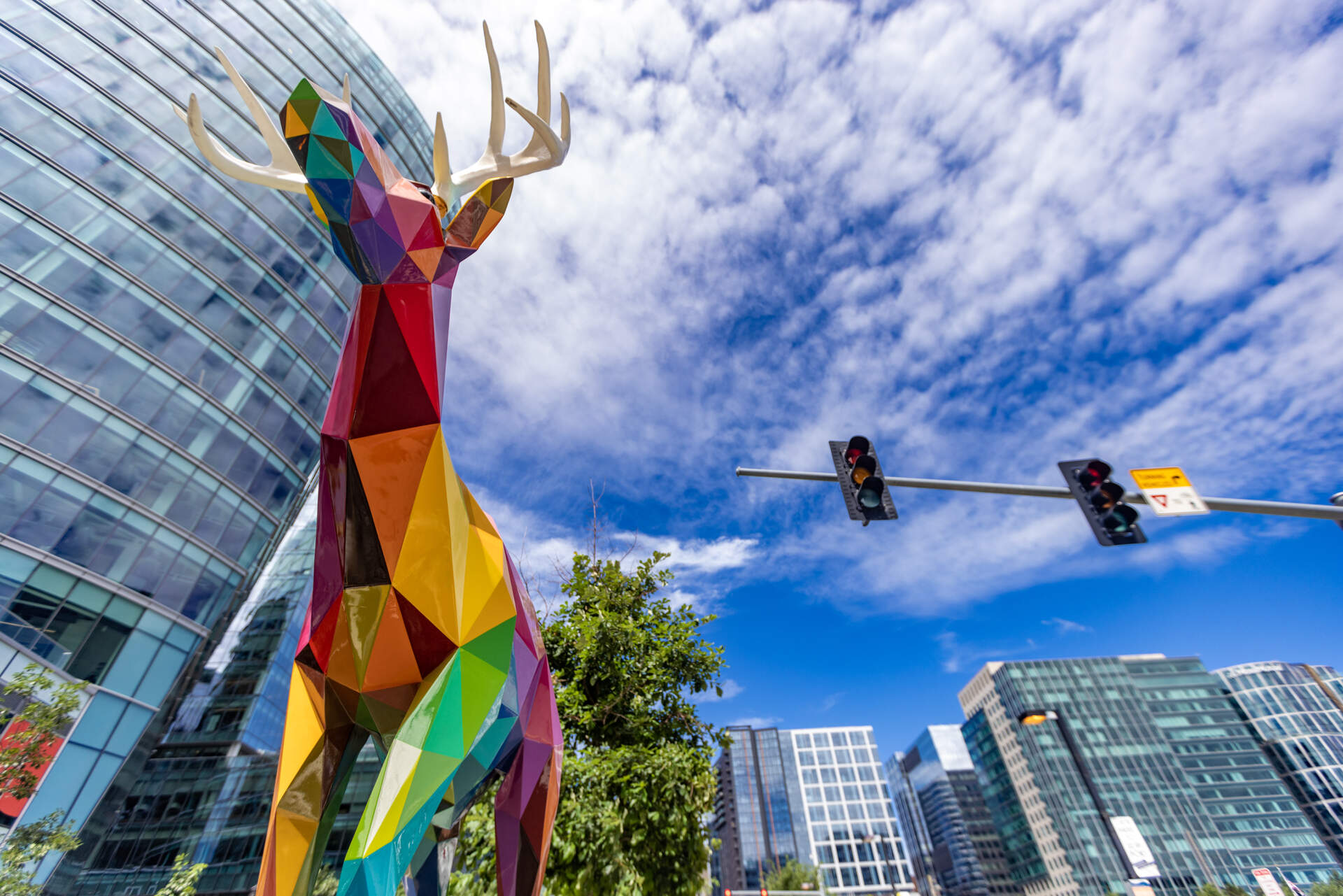 The multi-colored deer sculpture by Okuda San Miguel, which represents the wild creatures of the animal kingdom on Seaport Boulevard, stands among the tall glass buildings of the Seaport. (Jesse Costa/WBUR)