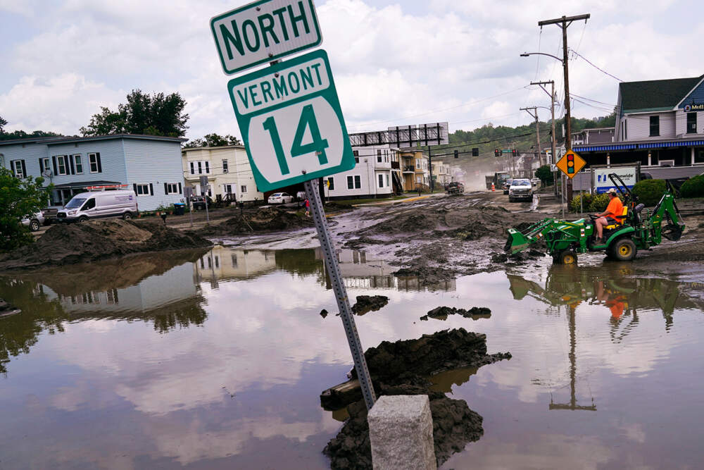 A small tractor clears water from a business as flood waters block a street, Wednesday, July 12, 2023, in Barre, Vt. Across the U.S., many people are living through one of the most brutal summers of their lives and reckoning with the idea that climate change is only going to make matters worse in the coming decades. (AP Photo/Charles Krupa, File)