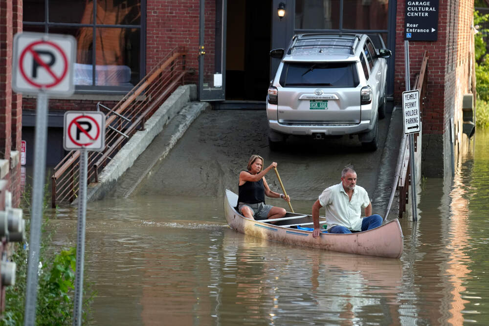 Jodi Kelly, left, practice manager at Stonecliff Veterinary Surgical Center, behind, and her husband, veterinarian Dan Kelly, use a canoe to remove surgical supplies from the flood-damaged center, Tuesday, July 11, 2023, in Montpelier, Vt. The supplies included orthopedic implants for an upcoming surgery on a dog. A storm that dumped two months of rain in two days brought more flooding across Vermont Tuesday. (AP Photo/Steven Senne)