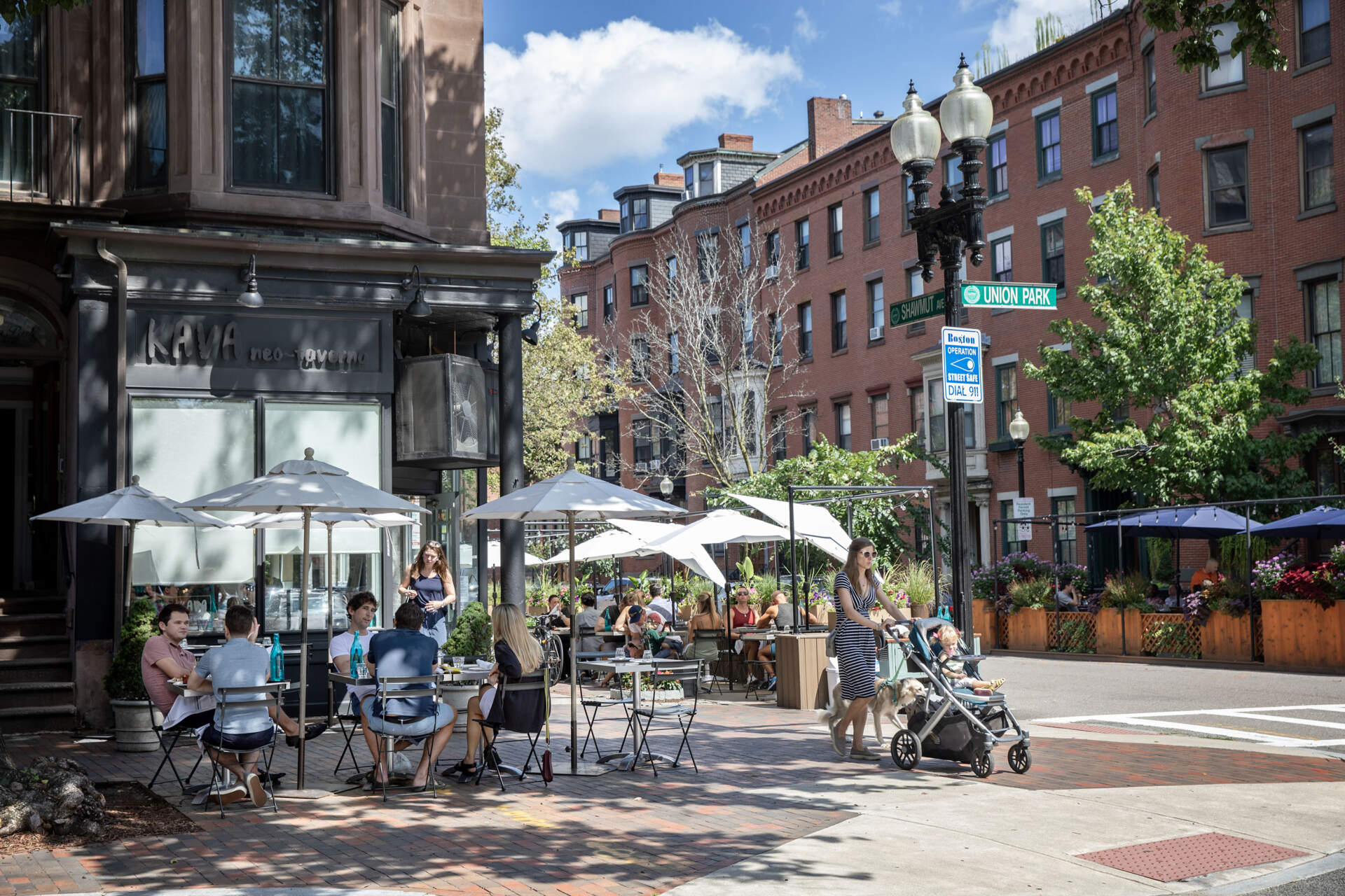 People at tables on the sidewalk at lunchtime by Kava Neo-Taverna on Shawmut Avenue in Boston. (Robin Lubbock/WBUR)
