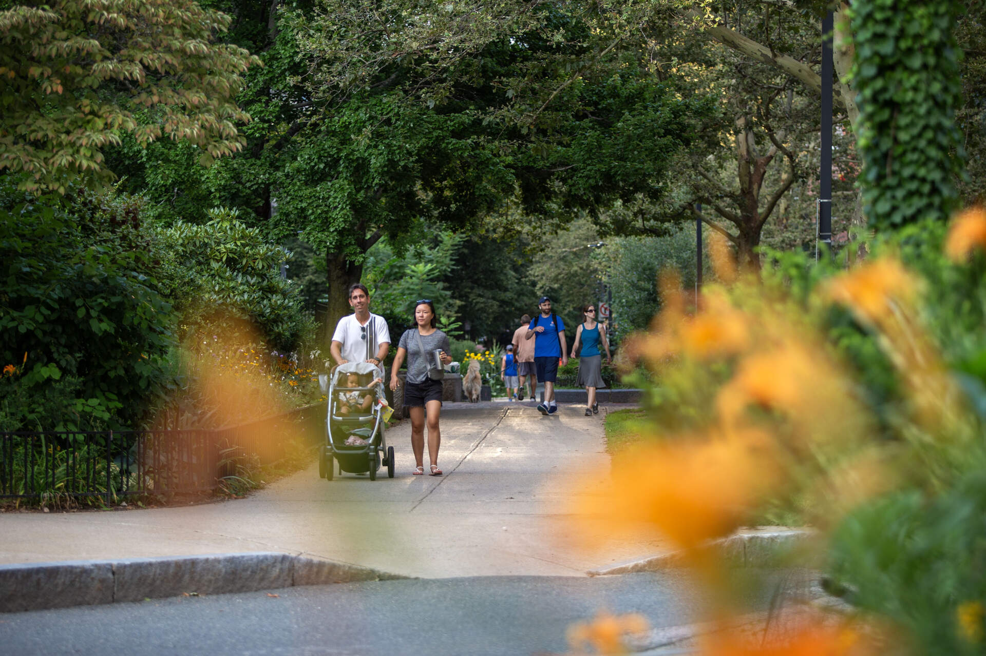 People walking in Southwest Corridor Park in Boston's South End, on a summer evening. (Robin Lubbock/WBUR)