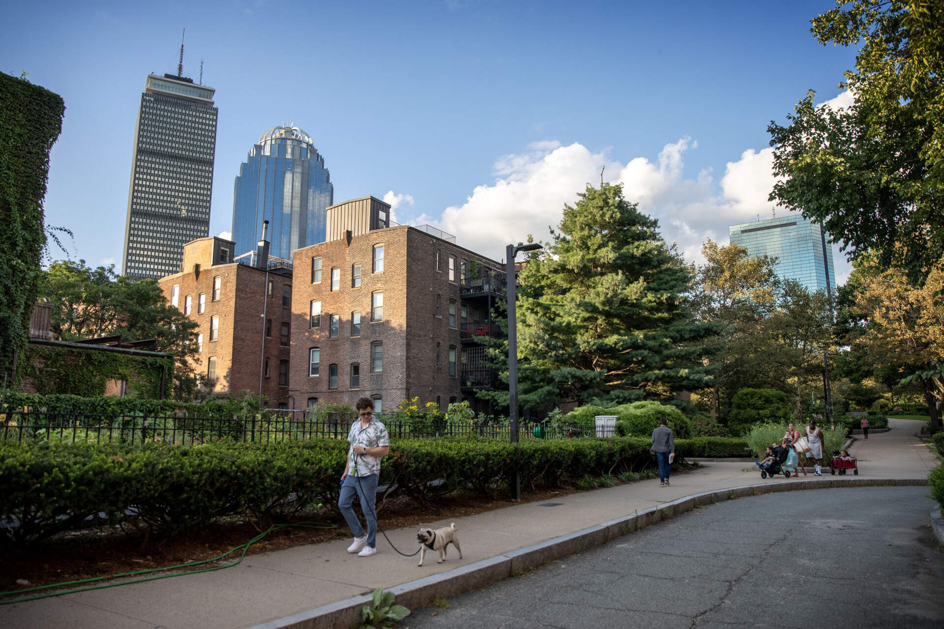 Residents enjoy green space in the South End. The Prudential Center peeks out behind residences. (Robin Lubbock/WBUR)