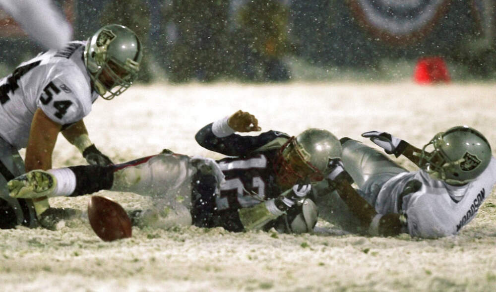 New England Patriots quarterback Tom Brady (12) loses the ball after being brought down by Oakland Raiders' Charles Woodson, right, while Greg Biekert (54) moves to recover the ball in the fourth quarter of their AFC Division Playoff game in Foxboro, Mass. Saturday night, Jan. 19, 2002. The play was appealed, and the Patriots retained possession. The Patriots went on to win, 16-13, in overtime. (Elise Amendola/AP)