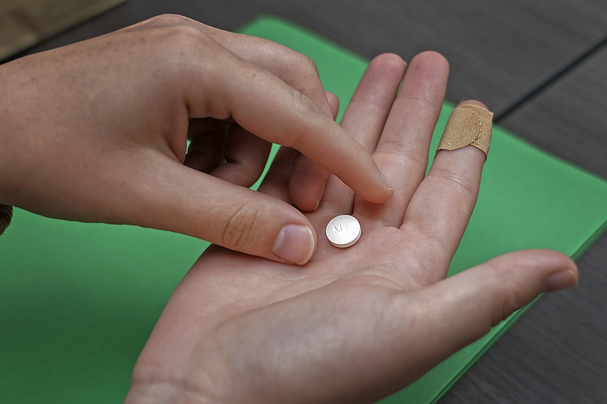 A patient prepares to take the first of two combination pills, mifepristone, for a medication abortion during a visit to a clinic in Kansas City. (Charlie Riedel/AP)