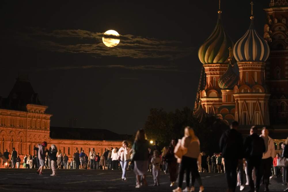 The August Super Blue Moon sets behind a historical building and the St. Basil's Cathedral, right, as people walk in Red Square in Moscow, Russia, Wednesday, Aug. 30, 2023. (Alexander Zemlianichenko/AP)