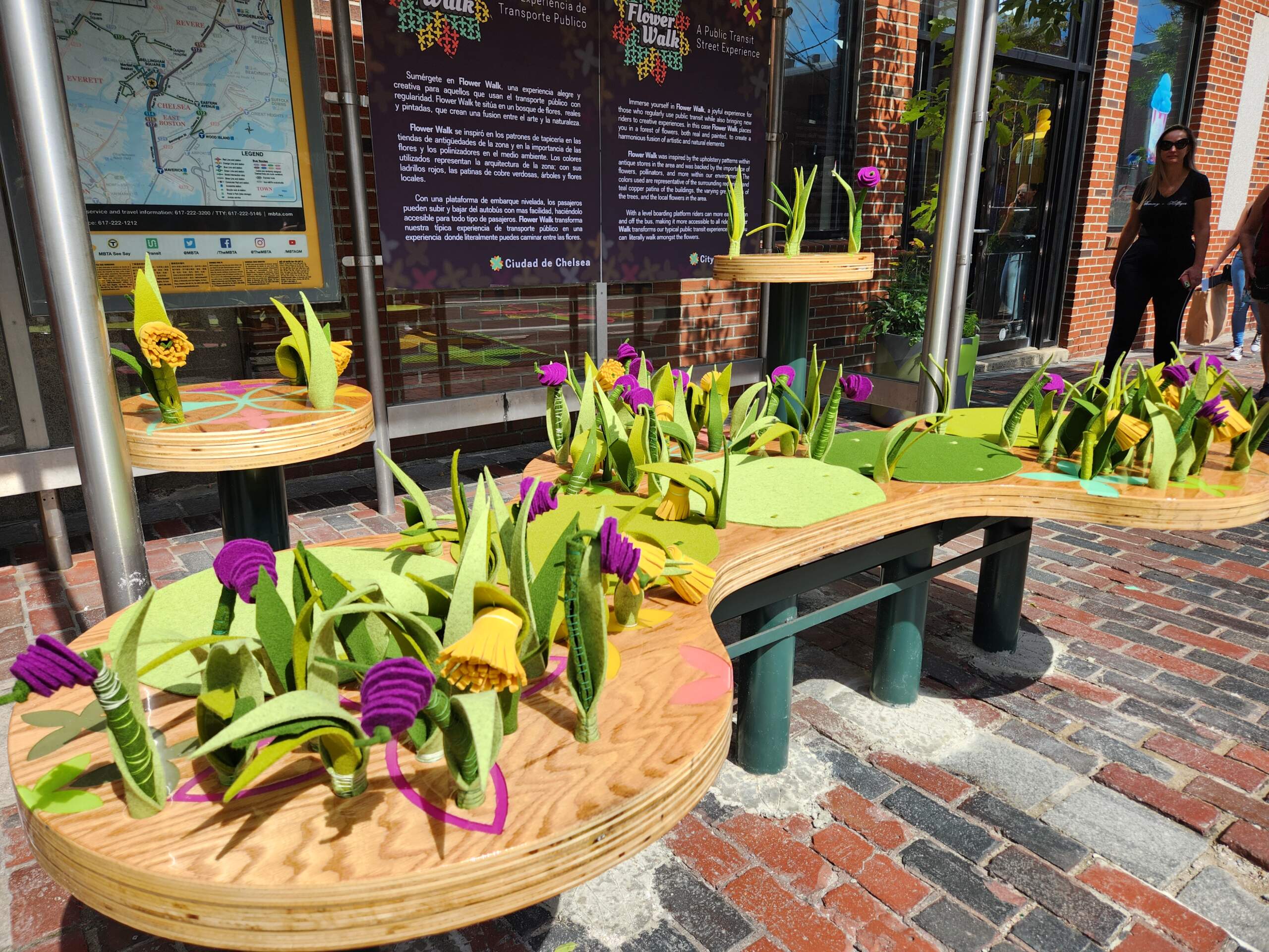 A bench filled in with flowers has been placed at the bus shelter located on Broadway and 3rd Street in Chelsea as part of the "Flower Walk" installation unveiled Aug. 22, 2023. (Andrea Perdomo-Hernandez/WBUR)