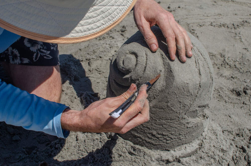 Gary White carves sand in to a spiral shape on Nahant Beach. (Sharon Brody/WBUR)