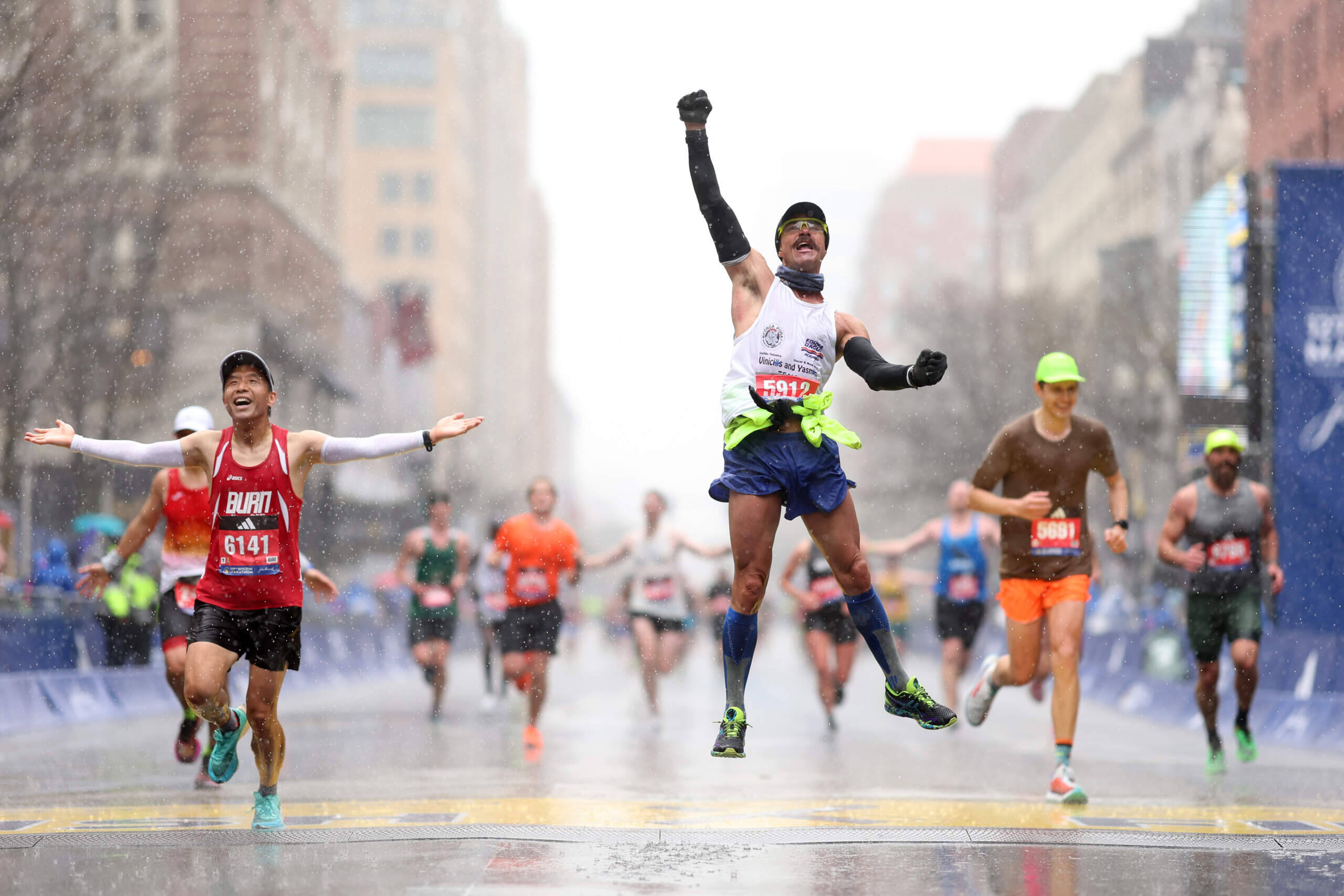 Fernando Ferreira celebrates in the rain as he crosses the finish line during the 127th Boston Marathon in 2023. (Maddie Meyer/Getty Images)