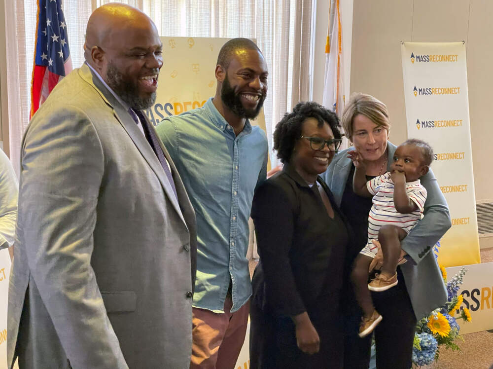 Secretary of Education Patrick Tutwiler, left, and Gov. Maura Healey, right, poses for a picture with MassBay student Danita Mends and family. (Max Larkin/WBUR)