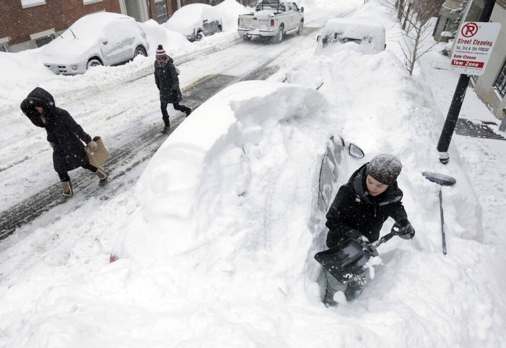 A woman shovels her car out of a snow pile in Beacon Hill neighborhood. (Steven Senne/AP)