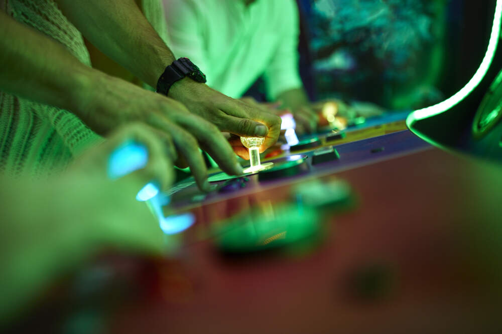 Close-up of friends playing at an arcade. (Westend61 via Getty Images)