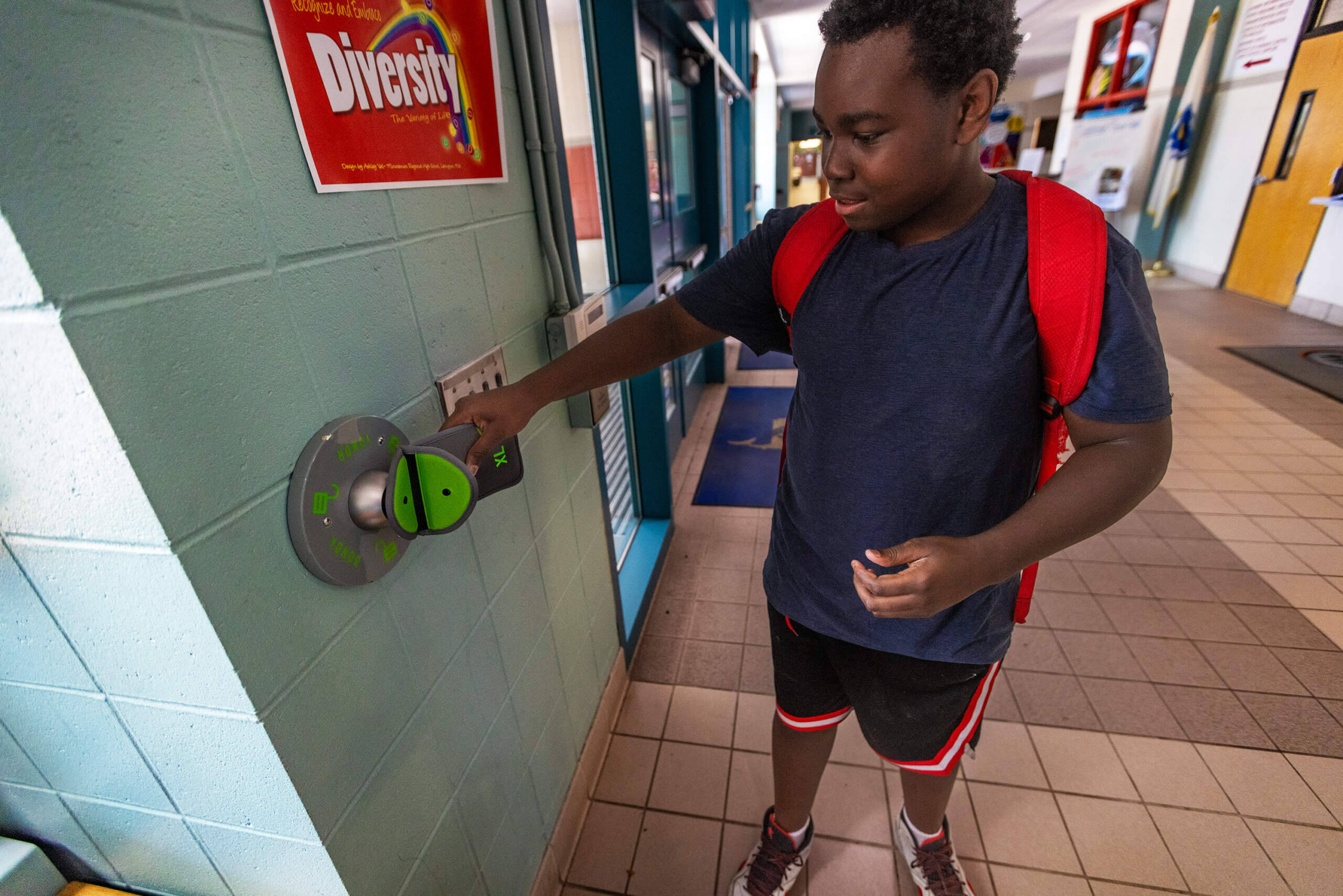 Eighth grader Tyri Bascomb opens his Yondr pouch by tapping it on the unlocking base at the Collins Middle School entrance. (Jesse Costa/WBUR)